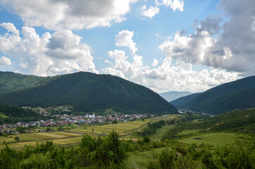 Fototapeta na wymiar Colorful landscape with green meadows and small village in Carpathian Mountains. Top view of mountain countryside. Kolochava, Transcarpathian, Ukraine