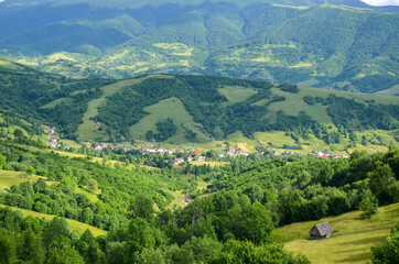 Obraz premium Colorful landscape with green meadows and small village in Carpathian Mountains. Top view of mountain countryside. Kolochava, Transcarpathian, Ukraine