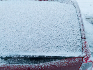 The rear window of the car is covered with snow and frost, making it difficult to see