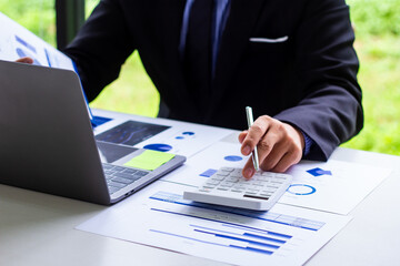 Male finance worker calculates last quarter's earnings figures and points to documents to present, business man checks company income and finance documents, modern business man concept.