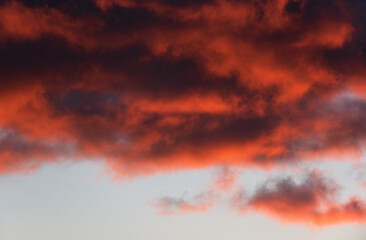 Cloudscape during sunset with beautiful orange and purple light illuminating the clouds from below.
