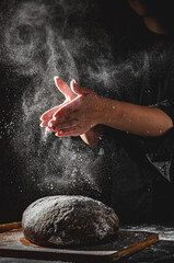 woman chef hand clap with splash of white flour and black background with copy space. woman's hands...