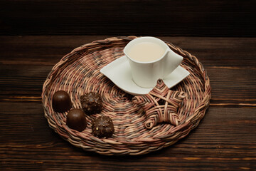 A cup of tea on a wicker tray. Chocolates.