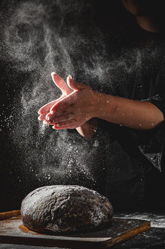 woman chef hand clap with splash of white flour and black background with copy space. woman's hands Making bread