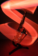 Saxophone instrument wrapped in vibrant light ribbons (red) - light trail photography using brass instruments as the subject.