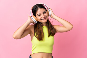 Young caucasian woman isolated on pink background listening music