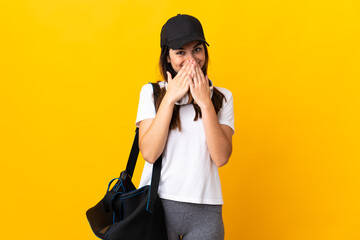 Young sport woman with sport bag isolated on yellow background happy and smiling covering mouth with hands