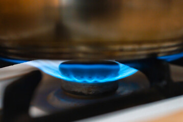 Steel Pot on the gas stove with burning flame in the kitchen.Soft focus.Close up.
