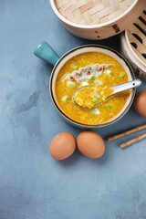 Chinese traditional egg-drop soup served with steamed dumpling, high angle view on a grey concrete background, vertical shot with space