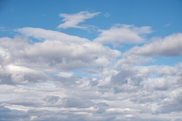 White fluffy clouds in the blue sky. Sky background with the fluffy white clouds.