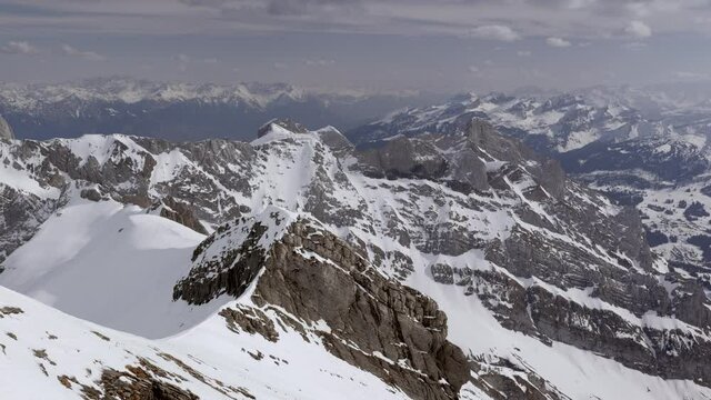 wide mountain landscape in snow filmed from above in the säntis area, ravens flying over the mountains, in the daytime without people