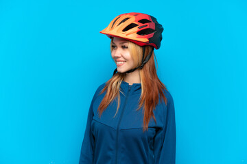 Young cyclist girl isolated on blue background looking side