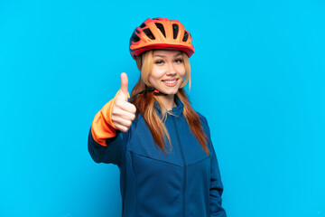 Young cyclist girl isolated on blue background with thumbs up because something good has happened