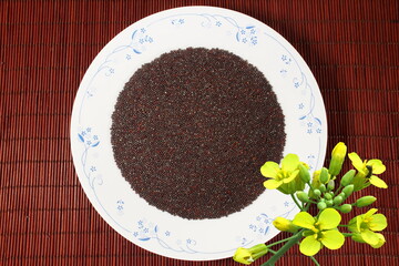 brown mustard seeds spice or rai in plate with mustard plant flower as food,health,garden related background - obrazy, fototapety, plakaty