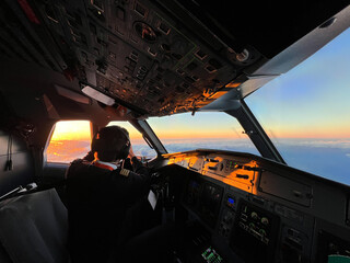 Pilots on the cockpit of an airliner flying at sunrise