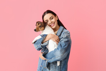 Happy young woman with cute dog on pink background