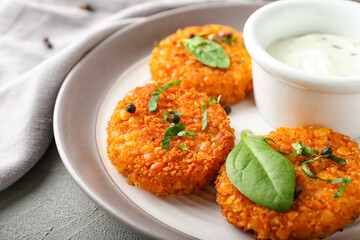 Plate with tasty lentil cutlets and sauce on grey background, closeup