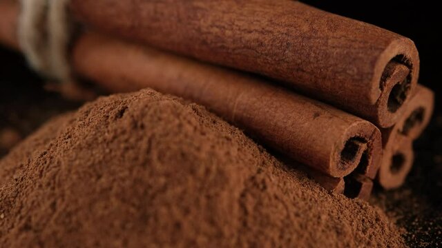 Cinnamon sticks and cinnamon powder isolated on black background, sliding shot. 4K UHD video