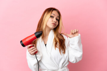 Teenager blonde girl holding a hairdryer over isolated pink background proud and self-satisfied