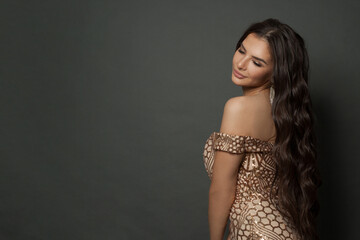 Young celebrity woman with long healthy curly hair on black background, fashion portrait