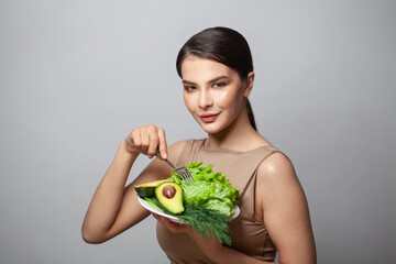 Woman holding green vegetables avocado and green herbs on plate. Healthy eating and diet concept