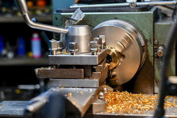 A turner bores a hole in a bronze part on a lathe with a power tool.