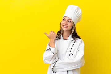 Young Russian chef girl isolated on yellow background pointing to the side to present a product