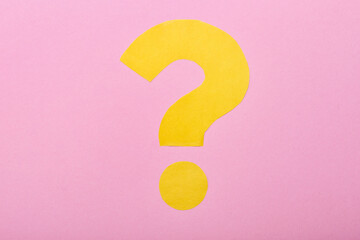 Question mark made of yellow paper on pink background