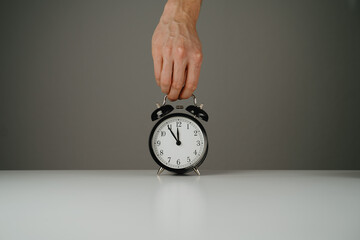 Hand holding black alarm clock
