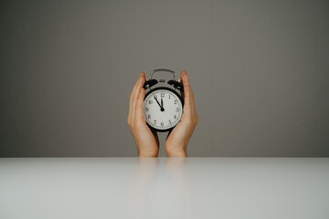 Two hands holding black clock