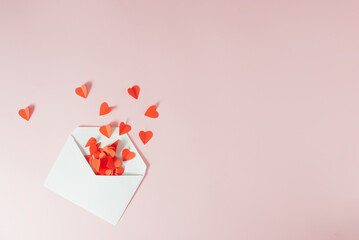 Red paper hearts falling out of the white envelope - Valentine's love card. Minimal concept.