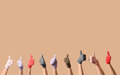 Women in warm gloves showing thumb-up gesture on beige background