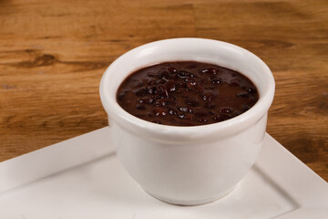 Delicious Slow Cooked Brazilian Black Beans. Served in a white bowl on a wooden table.