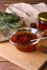 Bowl of tasty pine cone jam on wooden background
