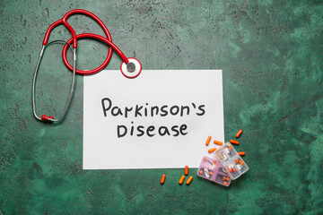 Paper sheet with text PARKINSON'S DISEASE, stethoscope and pills on green background