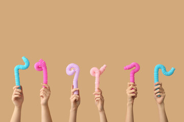 Hands with popular pop tubes on color background