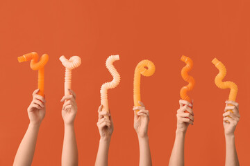 Hands with popular pop tubes on color background