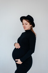 Pregnancy, motherhood, people and the concept of waiting - a close-up of a pregnant woman with a big belly in a black dress