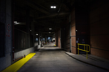 Fototapeta na wymiar Underground parking scene - Gloomy industrial scene - modern painted handrails - old concrete and brick structure - vehicle loading bay