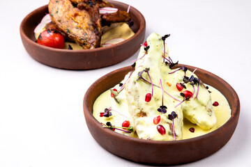 Chkmer chicken decorated with pomegranate on a light background