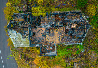 Aerial photo of the ruins of a burnt wooden house after fire. Lonely house surrounded by a forest
