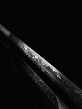 Macro in bianco e nero di una ringhiera in ferro arrugginito, illuminata dall'alto