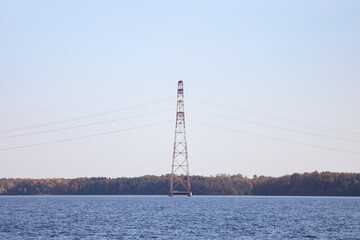 Landscape view of large metallic electricity pole in the middle of river connecting two shores.