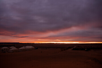 Fototapeta na wymiar Luxury glamping camp on sand in sahara desert against dramatic sky during sunset, Campsite over sand dunes in desert