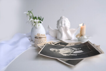 stack of vintage photos, baby photography of 1960, candle is lit, first spring flowers, snowdrop, Galanthus in vase, concept of family tree, genealogy, childhood memories