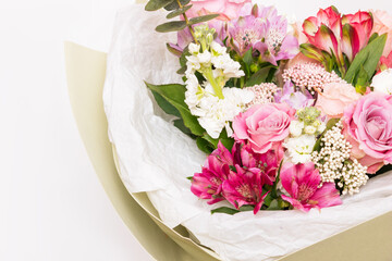 Close-up of a bouquet of colorful pink roses in a stylish festive package on a white background. Flowers, spring. Copy space for text or design