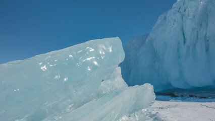 A thick shiny turquoise ice floe against the blue sky. The glare of the sun on the edges. Close-up....