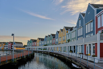 Row of colourful wooden newly built Dutch houses surrounded by water of lake De Rietplas in Houten in the Netherlands.