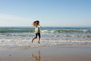 pretty girl full of vitality running and jumping on the sunny beach