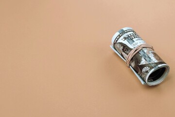Roll of one hundred dollar bills close-up on a beige background. Copy space